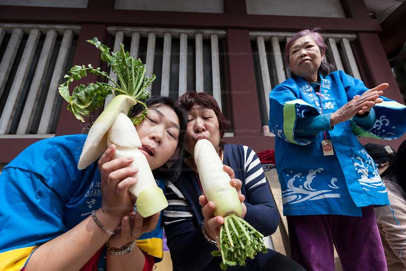Women posed with phallus-shaped radishes